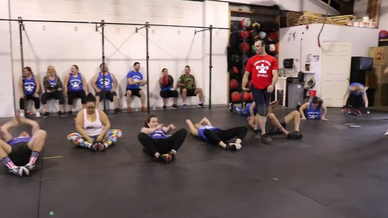 Members exercising together in a wide floor circle, cheering each other on